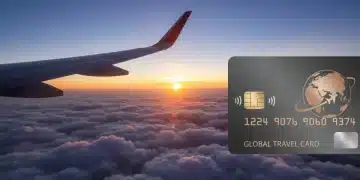 Airplane wing over clouds with travel credit card reflecting sunset